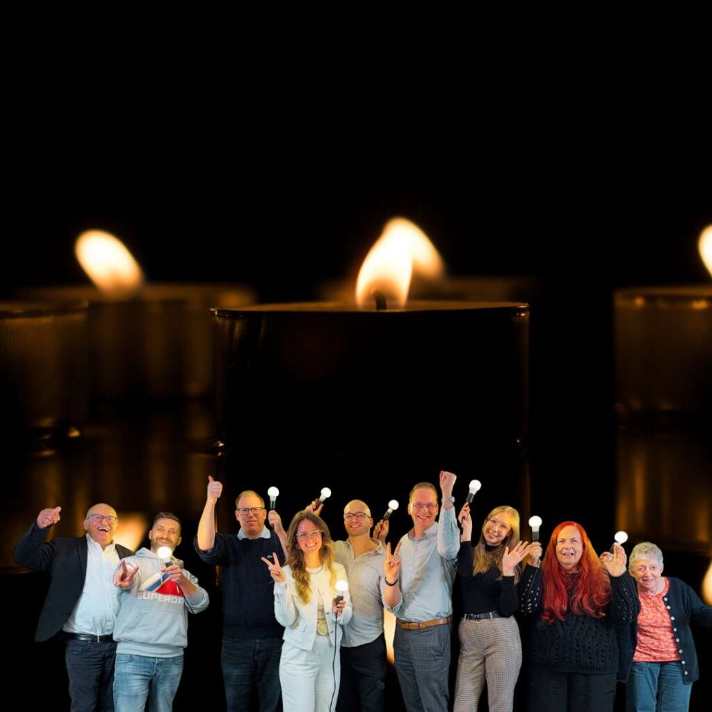 Gruppenfoto vor Kerzenlicht, Personen halten kleine Lichter in der Hand